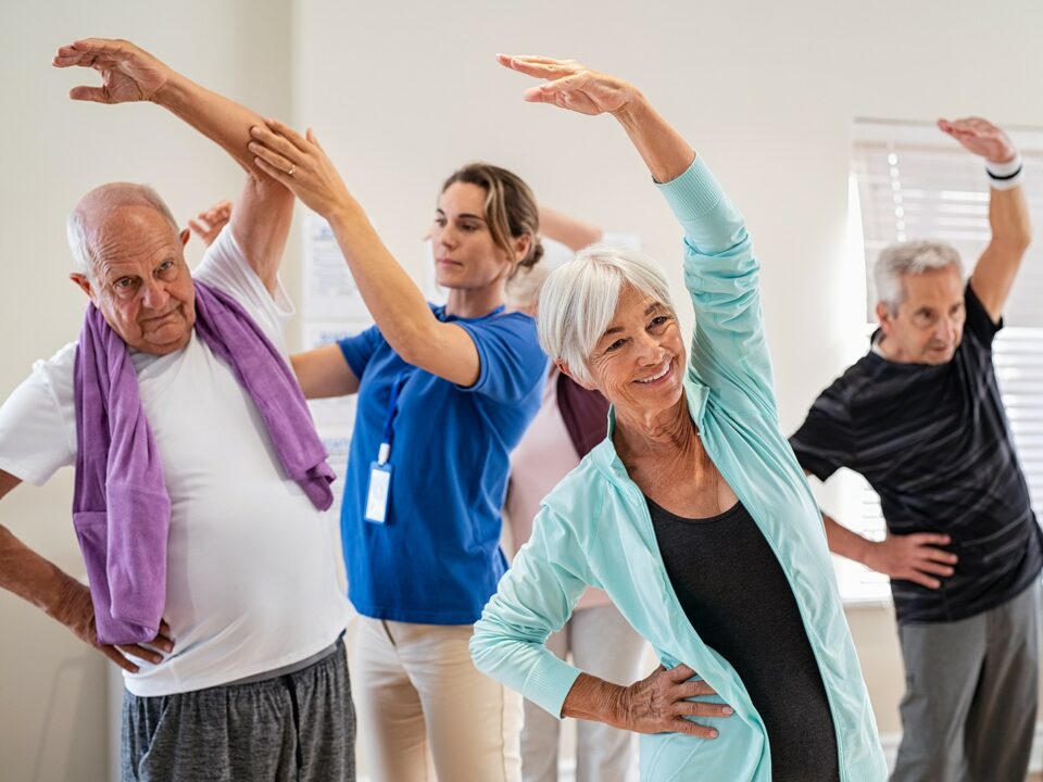 Group of seniors taking an exercise class in a senior living facility.