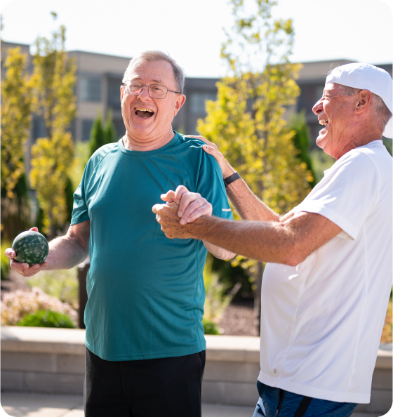 Community members laughing together outside during a game of bocce ball.