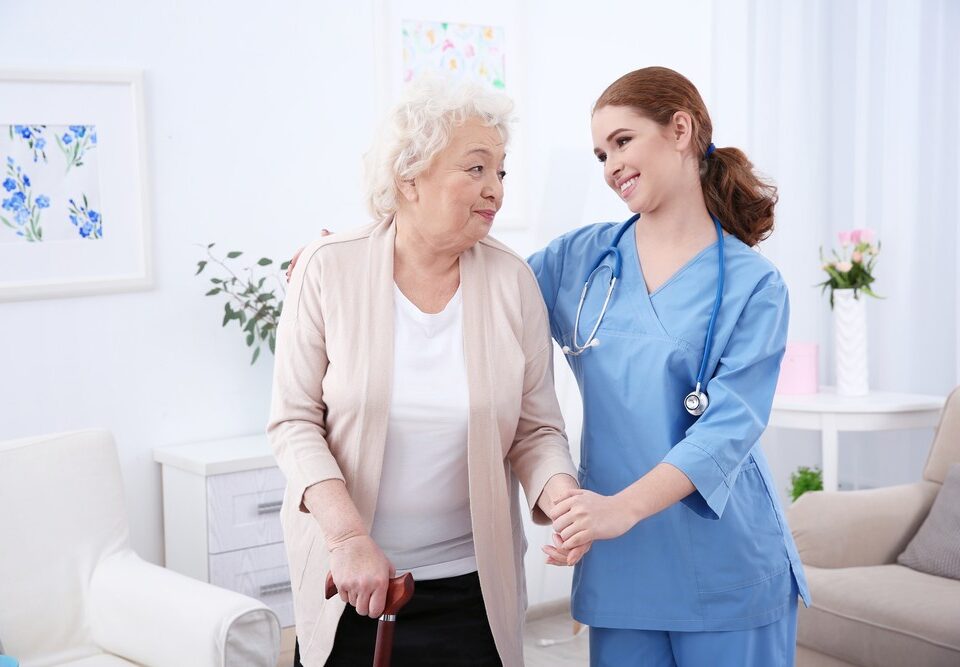 Senior woman walking with help from nurse.