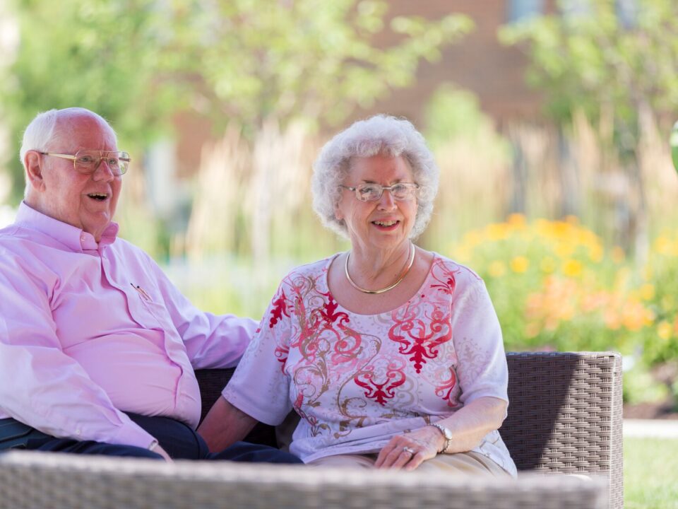 A senior couple enjoy a sunny day on the patio.