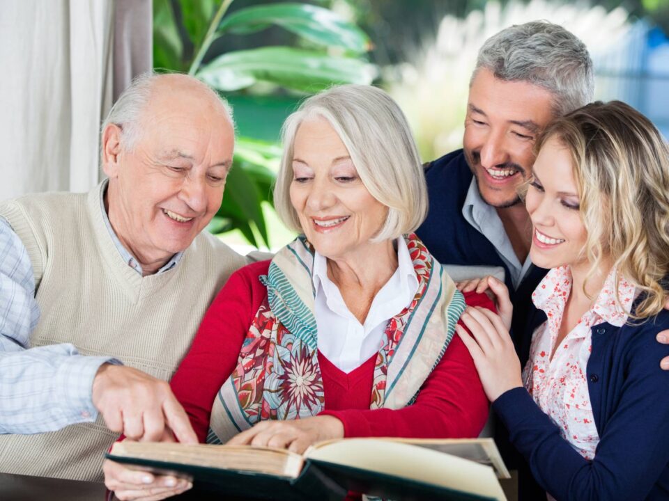 happy seniors looking at a photo album with family