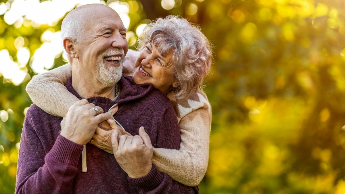 Senior couple smiling outside.