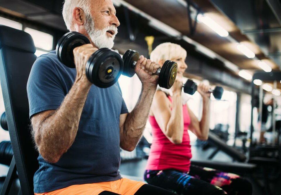 a senior couple working out in a gym by lifting weights