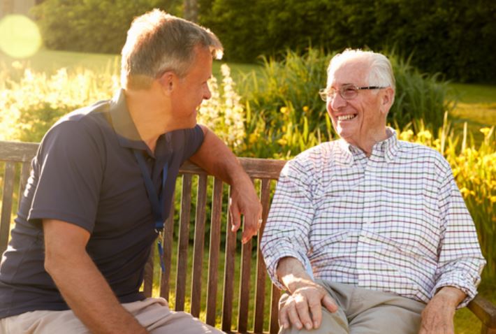 Two senior men sitting on a bench laughing