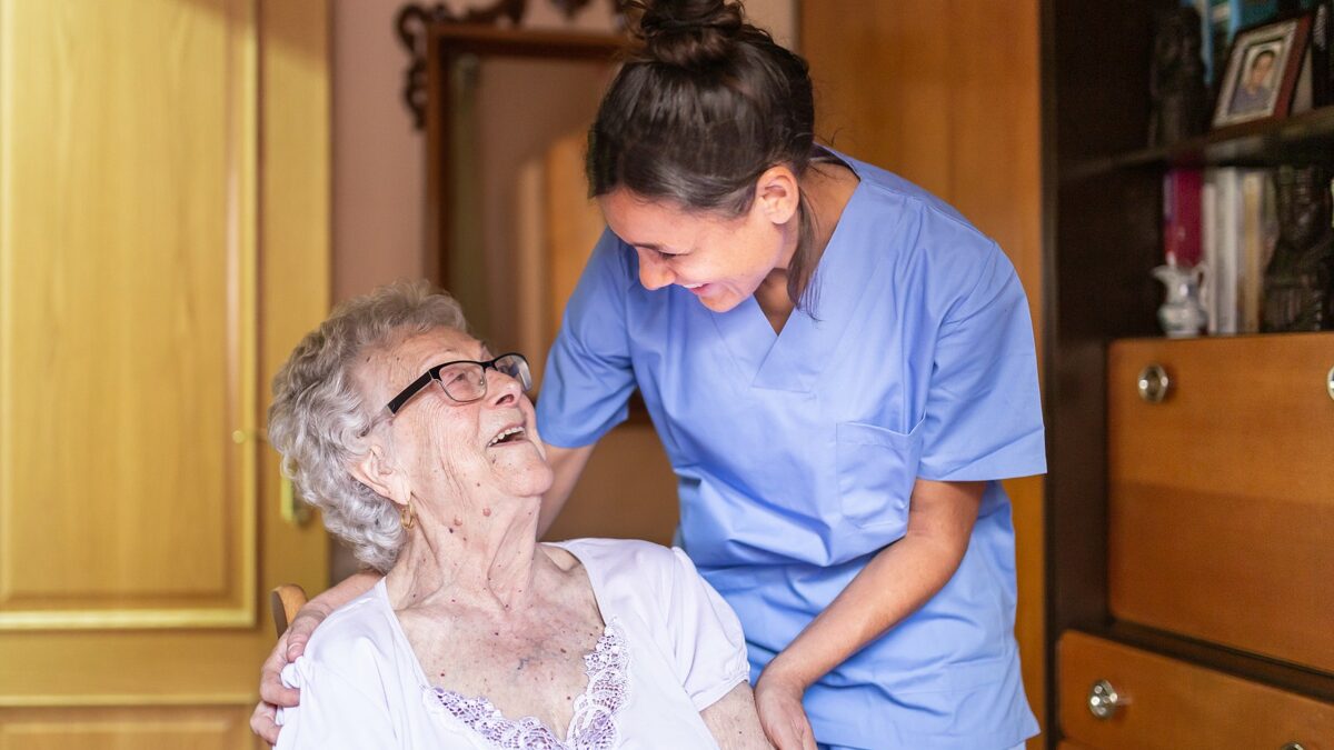Senior woman and home care nurse laughing together.