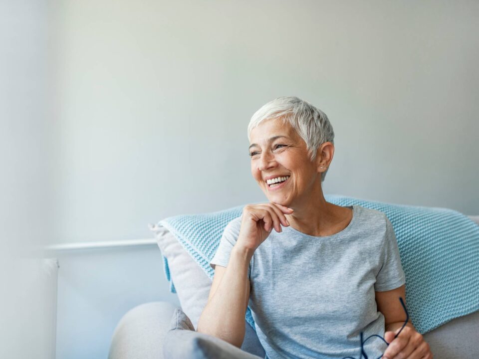 senior lady smiling while sitting on a couch