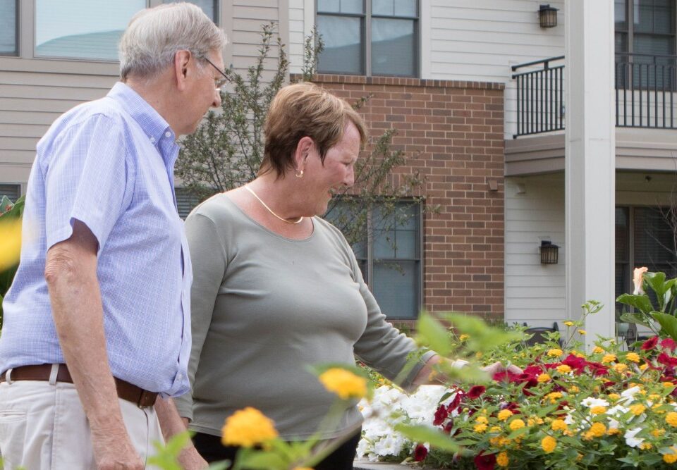 senior couple enjoying flowers outside apartments