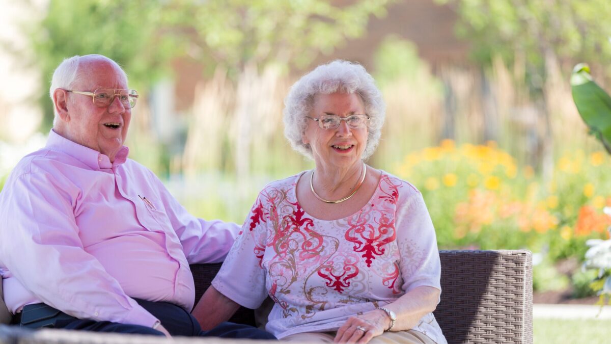 A senior couple enjoy a sunny day on the patio.