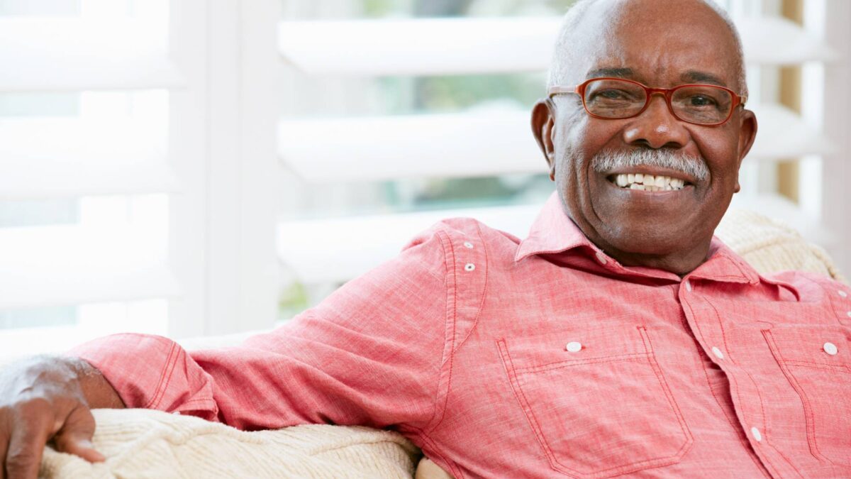happy senior sits on the couch of his senior apartment