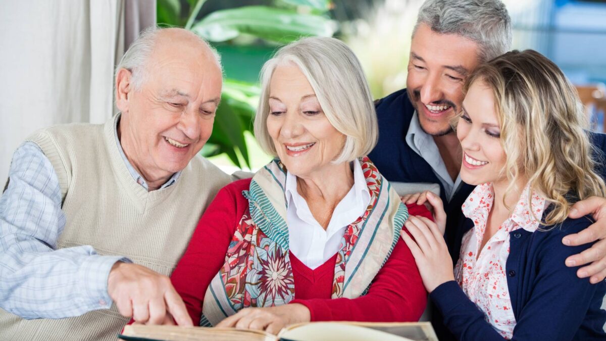 happy seniors looking at a photo album with family